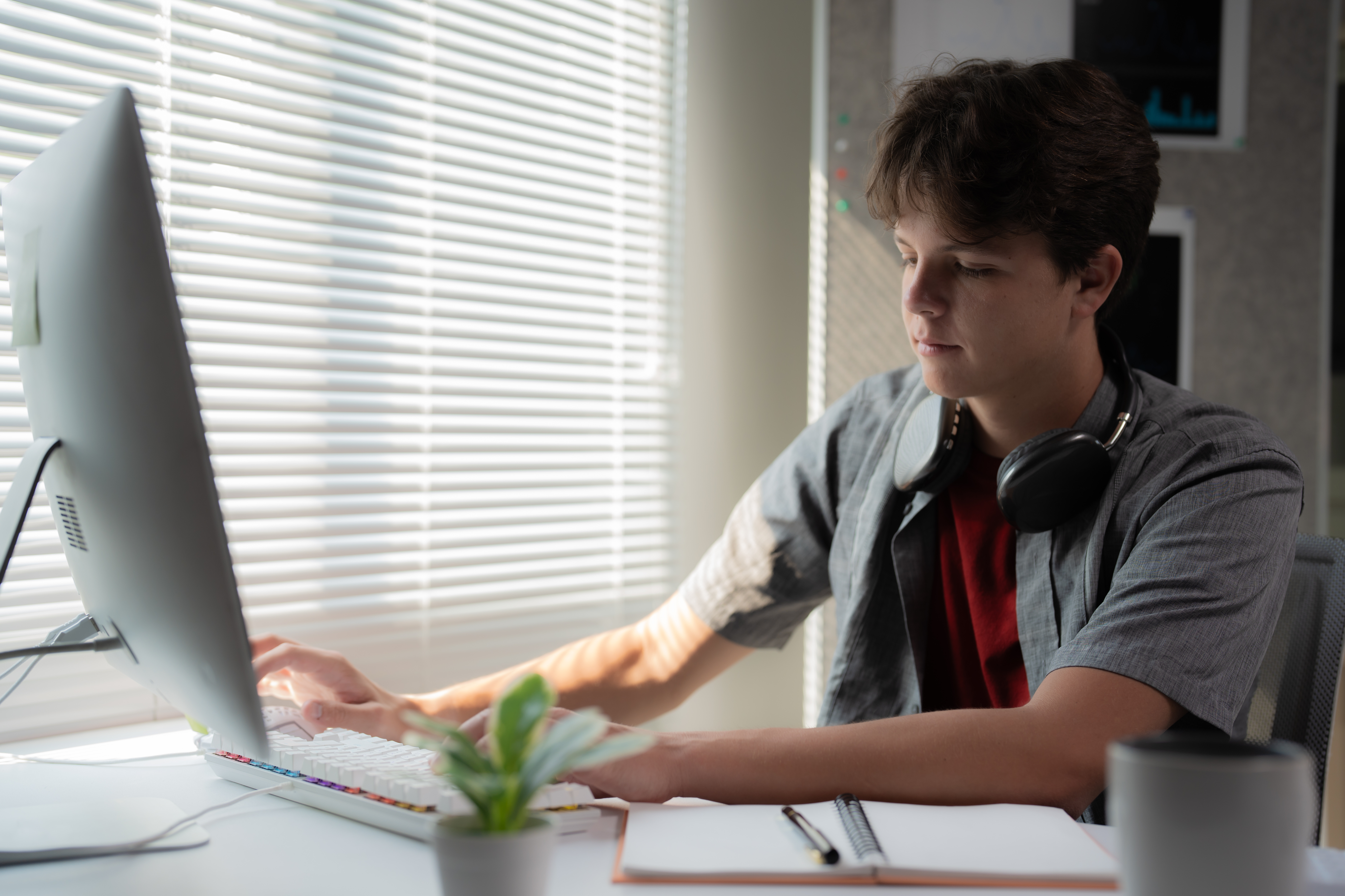 Young man focused on computer work in a bright home office.